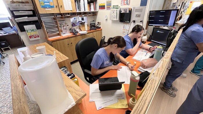 Des infirmières travaillent derrière un comptoir. 