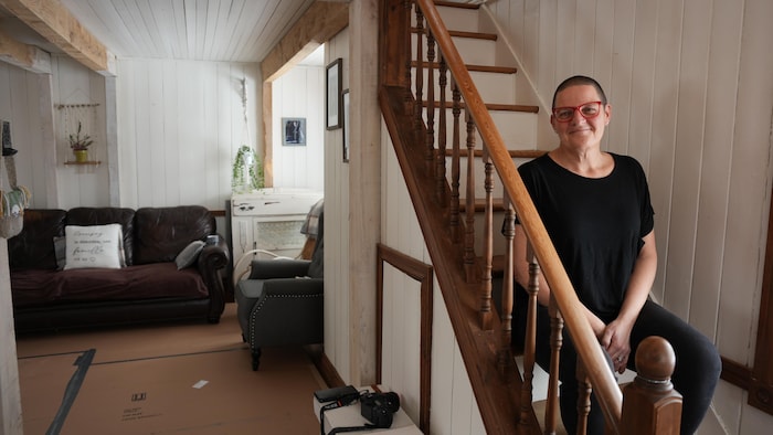 Isabelle Cummings assise dans les escaliers de sa maison, à Fatima, aux Îles-de-la-Madeleine, en mars 2025.