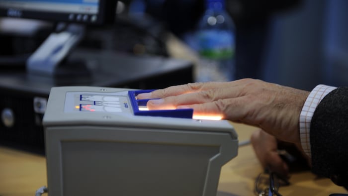 Une personne fait numériser ses empreintes digitales par une machine.