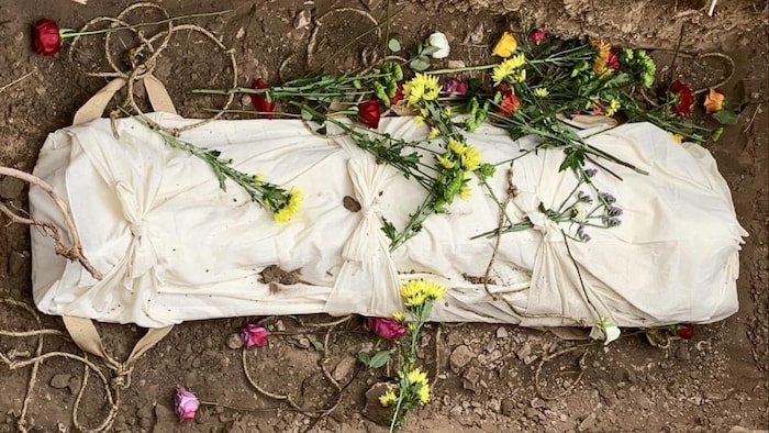 Un linceul qui recouvre un corps avec des fleurs.