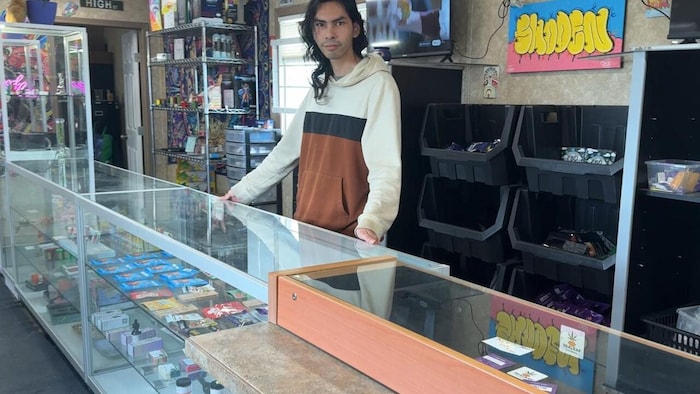 Un vendeur de cannabis derrière le comptoir de sa boutique.