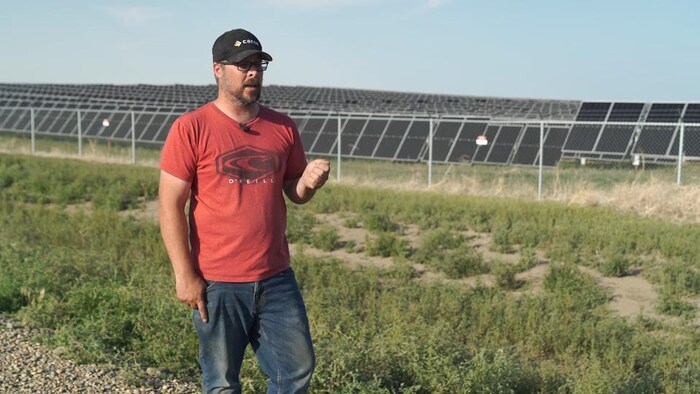 Jason Schneider devant des panneaux solaires.