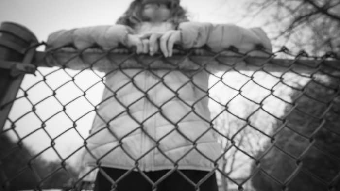  Une jeune fille accoudée à une clôture.