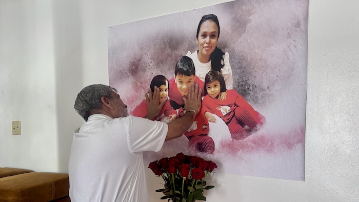 Un homme a les deux mains posées sur une image des victimes.