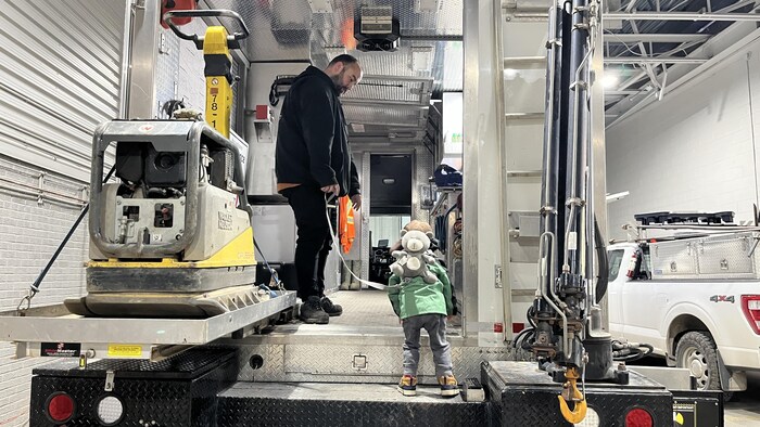 Un enfant explore une plateforme sous le regard attentif de son père.