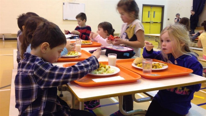 Des enfants mangent leur repas dans une cafétéria scolaire du Nouveau-Brunswick.