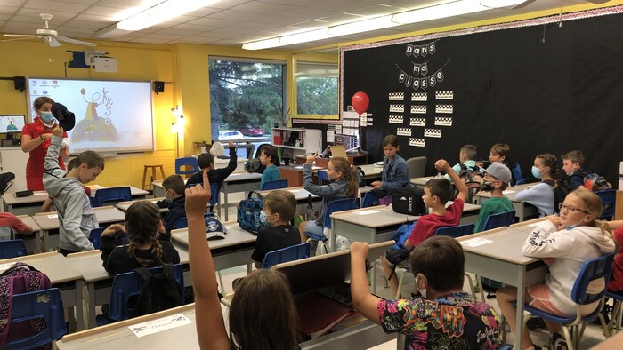 Des enfants se trouvent dans une classe en compagnie de leur enseignante.