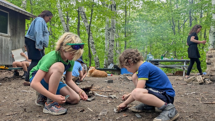 Des enfants allument un feu au sol.