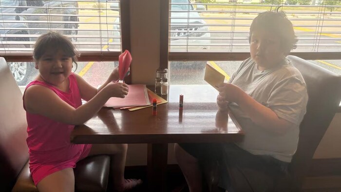 Deux enfants assis à une table font de l'artisanat.