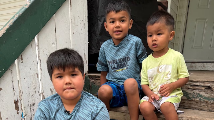 Jayce Whitstone assis avec deux autres enfants devant l'entrée d'une maison.