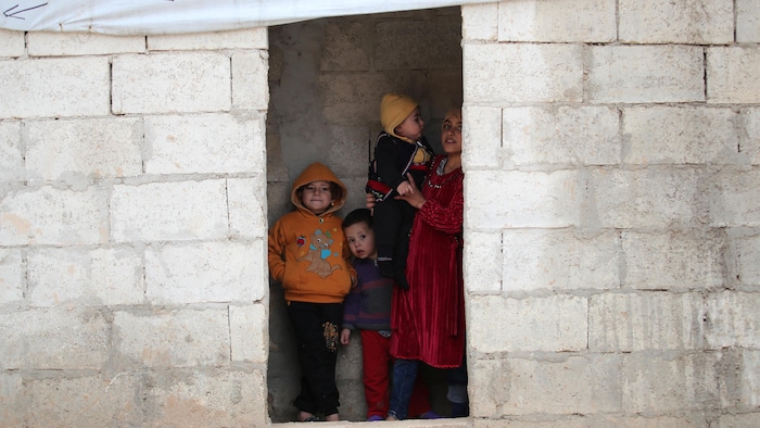 Cuatro niños en el umbral de un edificio sin puerta.