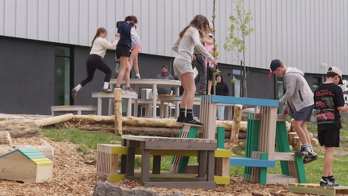 Des enfants jouent sur des structures de bois.
