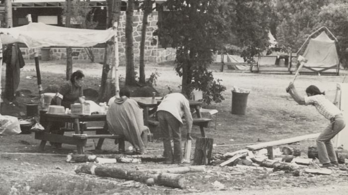 Des gens s'affairent autour d'un petit campement.