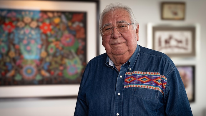 Tony Belcout debout devant une oeuvre d'art.
