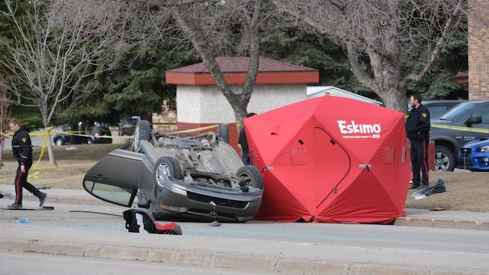 Une voiture renversée à côté d'une tente. 