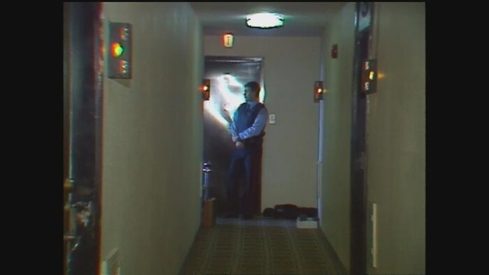 Un individu qui se tient au fond d'un corridor d'appartements.