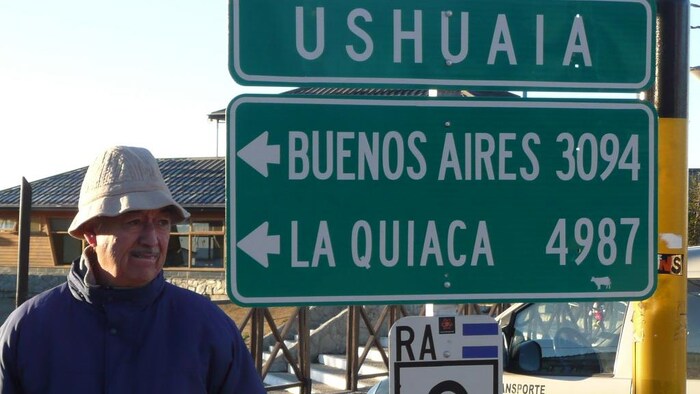Enrique Colombino à côté d'une enseigne qui indique des distances routières.