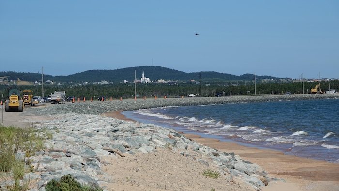 Une route bordée d'un enrochement à côté de la mer.