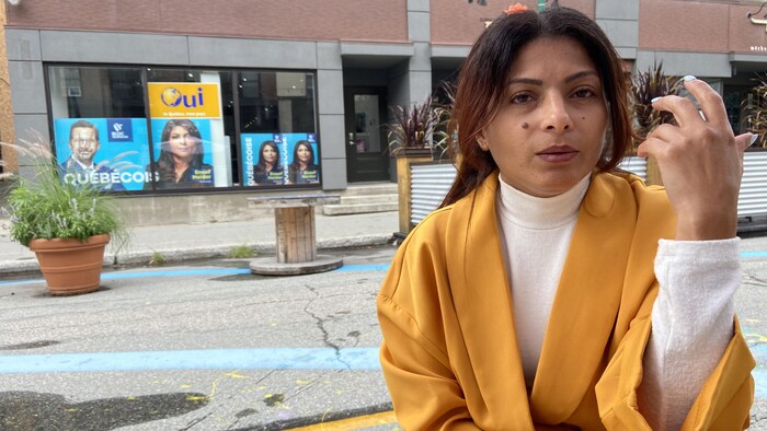 Une femme attablée en train de parler en levant sa main.