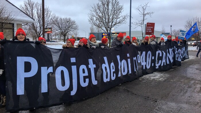Des manifestants portent une banderole sur laquelle on peut lire : Projet de loi no 40 : ça ne passe pas.