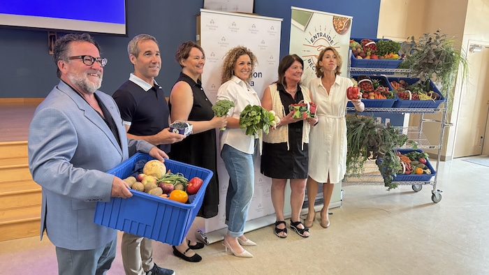 Des personnes avec des légumes dans les mains font la pose.