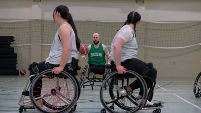 L'entraîneur Reid Richard entre deux athlètes en fauteuil roulant.