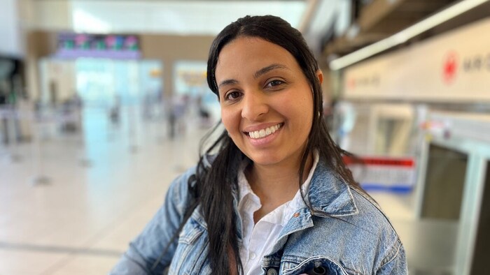Bruan Machado est debout dans un aéroport et sourit à la caméra. 
