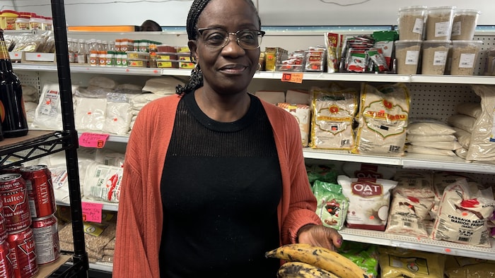 Une personne debout et tenant en main un produit alimentaire dans une épicerie.
