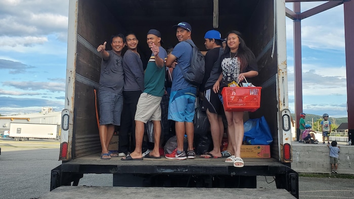 Des personnes attendent pour faire l'épicerie dans la remorque d'un camion.