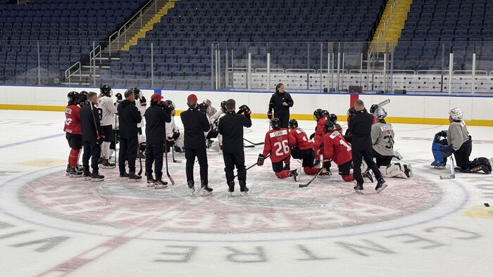 L'entraîneuse Kori Cheverie donne ses explications à des joueuses sur la glace.