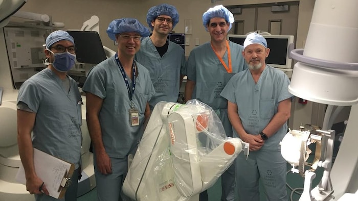 Des médecins posent avec un robot chirurgical dans une salle d'opération.