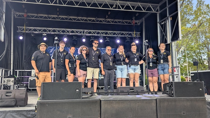Dix membres du comité posent sur une scène, tous vêtus du chandail de la Foire gourmande.