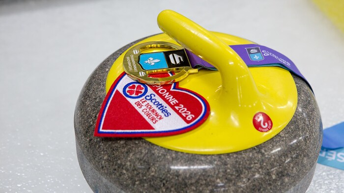 Une pierre de curling avec un écusson du Tournoi des Coeurs dessus.