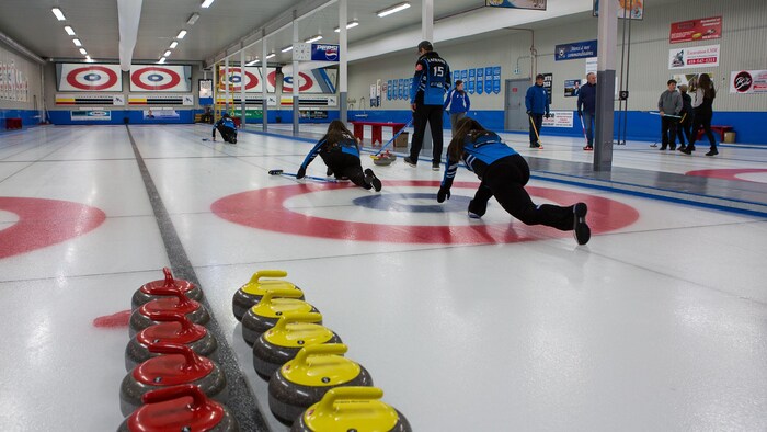 Une équipe de curling en entraînement sur la glace.