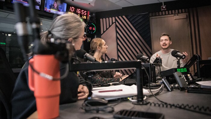 Dans un studio de radio, deux femmes et un homme discutent du menu de l'émission.