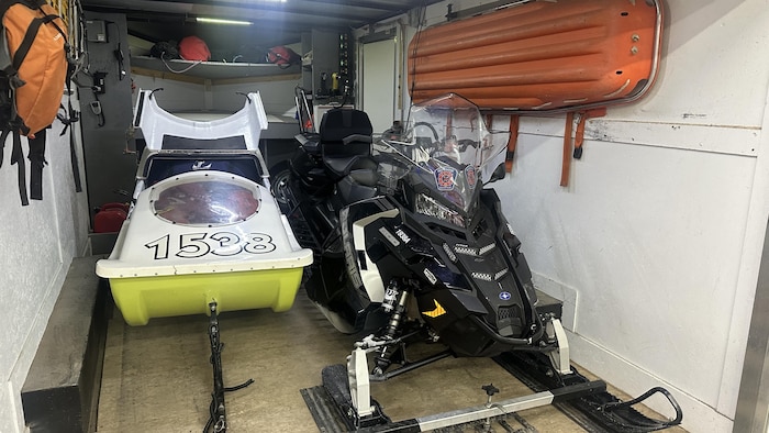 Une motoneige, des traîneaux et des civières dans un rangement.