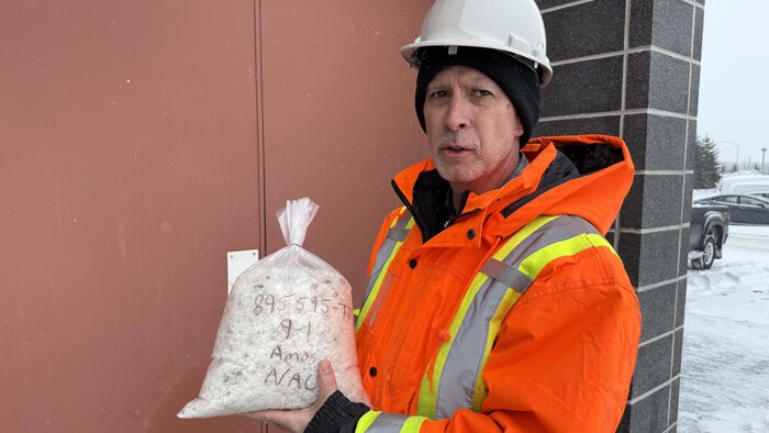 Un homme tient en main un sac plein de sel.