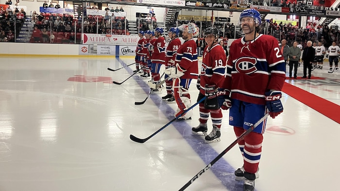 Éric Desjardins et d'autres joueurs des Anciens Canadiens debout sur leur ligne bleue lors d'une présentation d'avant-match.
