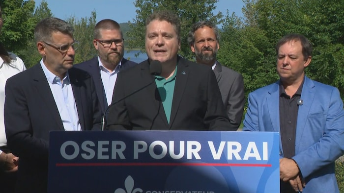 Cinq hommes devant un podium donnent une conférence de presse