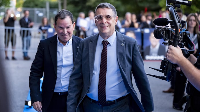 Éric Duhaime marche, décidé devant une caméra.