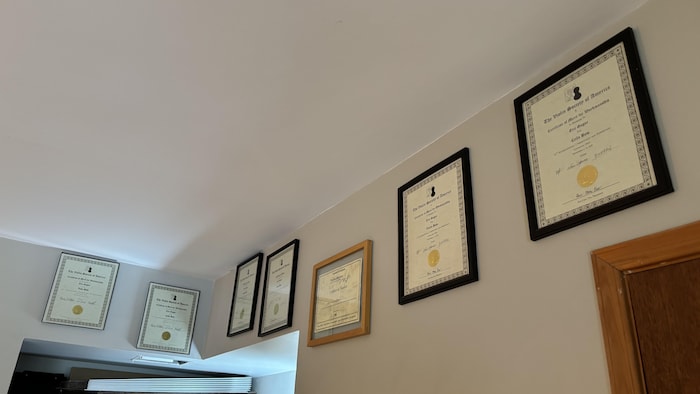 Des certificats accrochés au mur de son atelier.