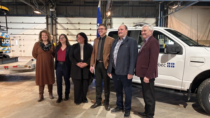 Trois femmes et trois hommes prennent la pose alors qu'un camion avec le logo du Québec se situe derrière eux.