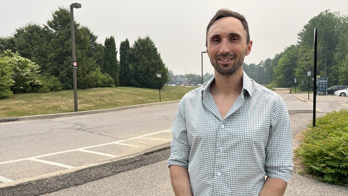 Une personne sourit à la caméra.