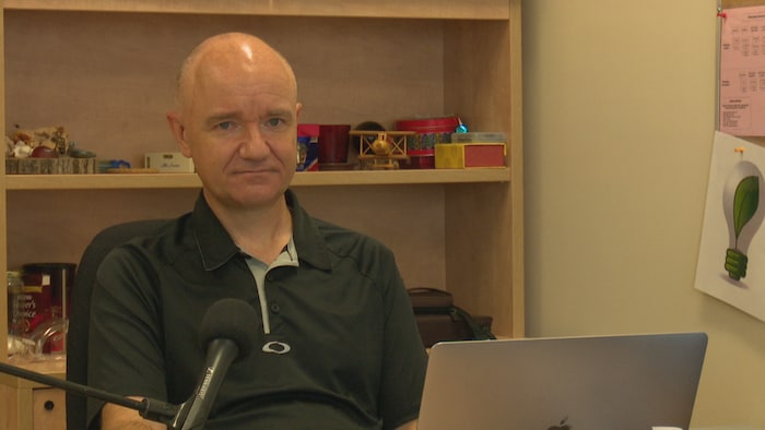 Éric Lavoie est assis derrière un bureau.