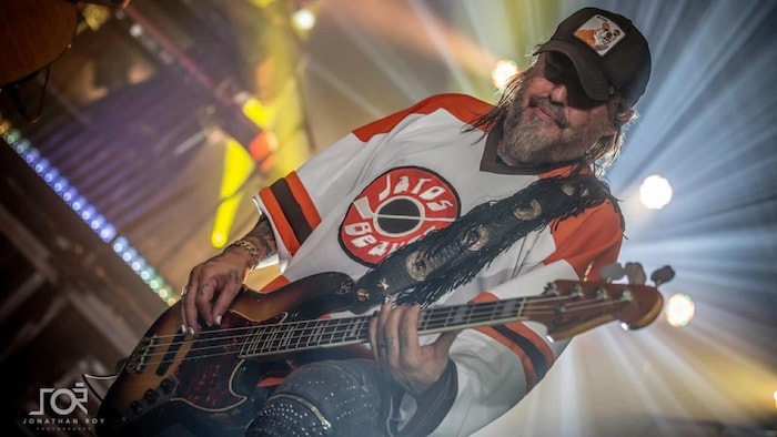 Un homme avec sa basse sur scène pendant un spectacle.