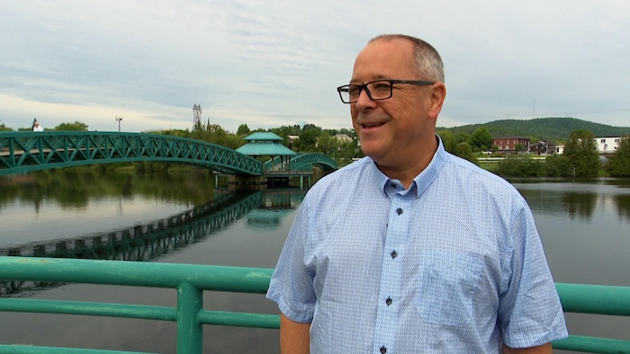 Un homme souriant devant un pont à Edmundston. 
