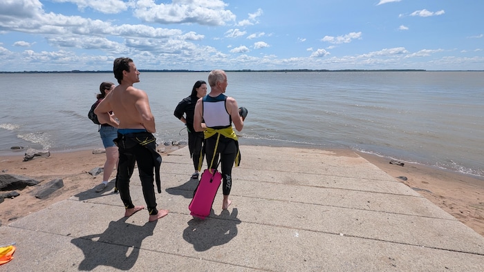 Quatre personnes regardent le fleuve Saint-Laurent avant leur départ.