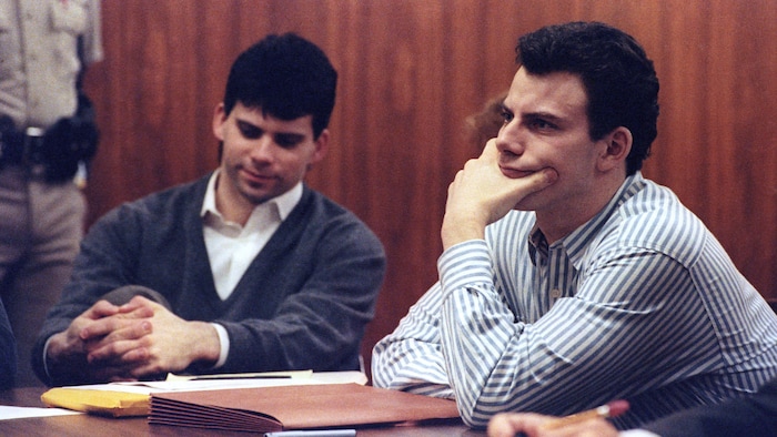 Deux hommes portant une chemise sont assis dans une salle de Cour.