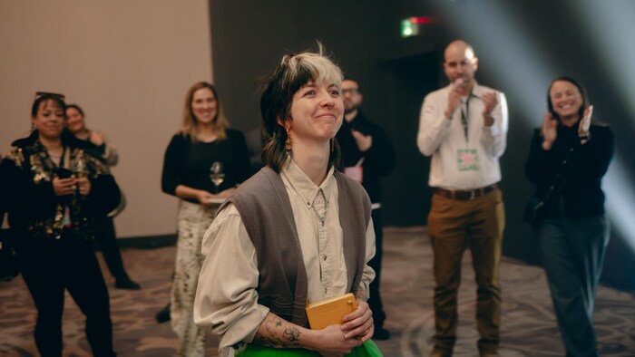 La jeune artiste a le sourire aux lèvres et marche vers le lutrin. 