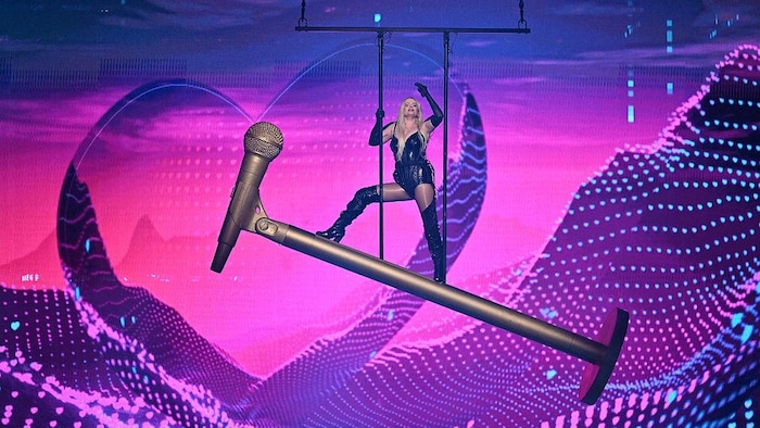 Une femme est juchée sur un micro géant dans les airs.